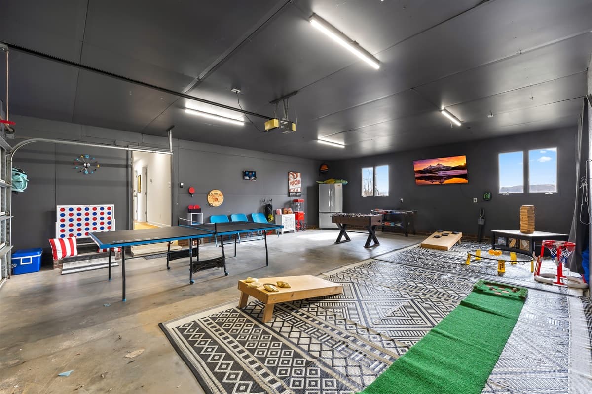 The game room includes a pool table, cornhole boards, and a mounted TV for rainy-day fun.
