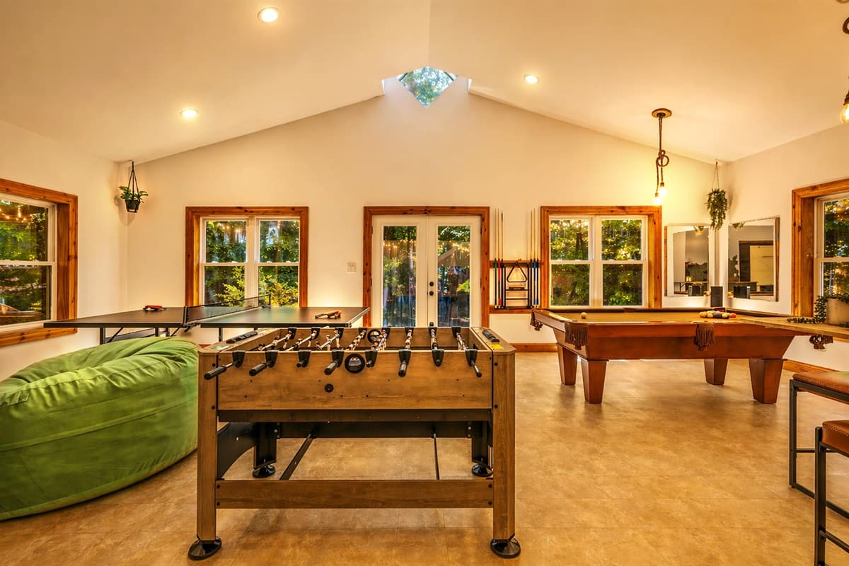 The game room delivers head-to-head fun with a foosball table and a pool table under a vaulted, wood-beamed ceiling.