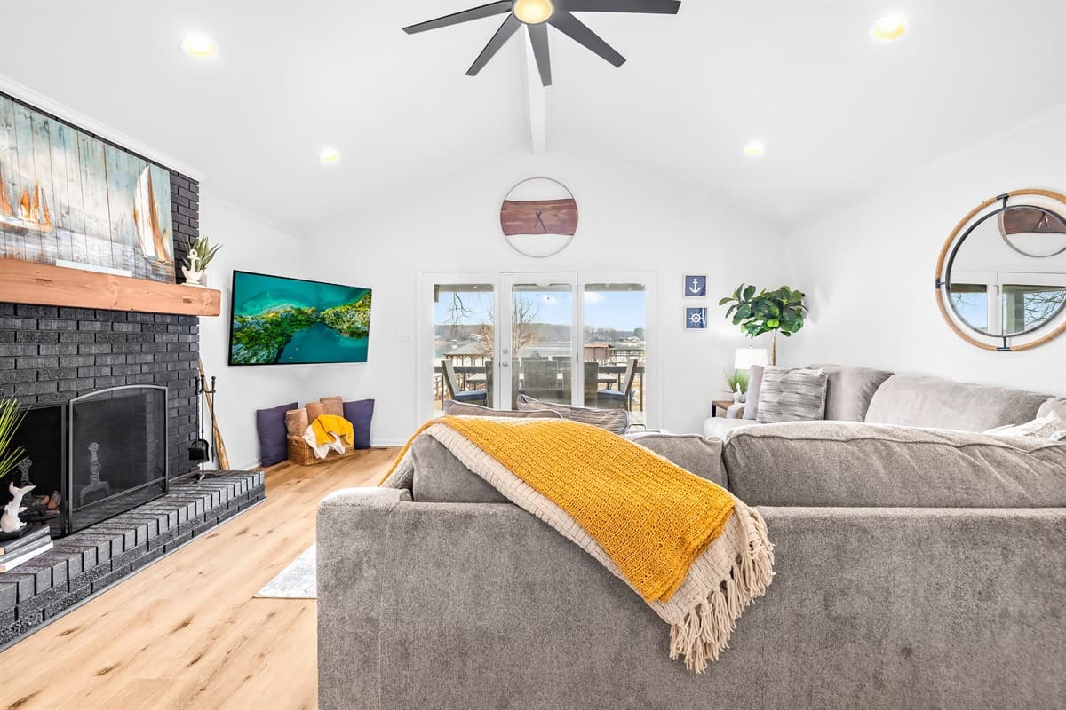 The living room has a sectional sofa and a mounted TV, with a ceiling fan overhead.