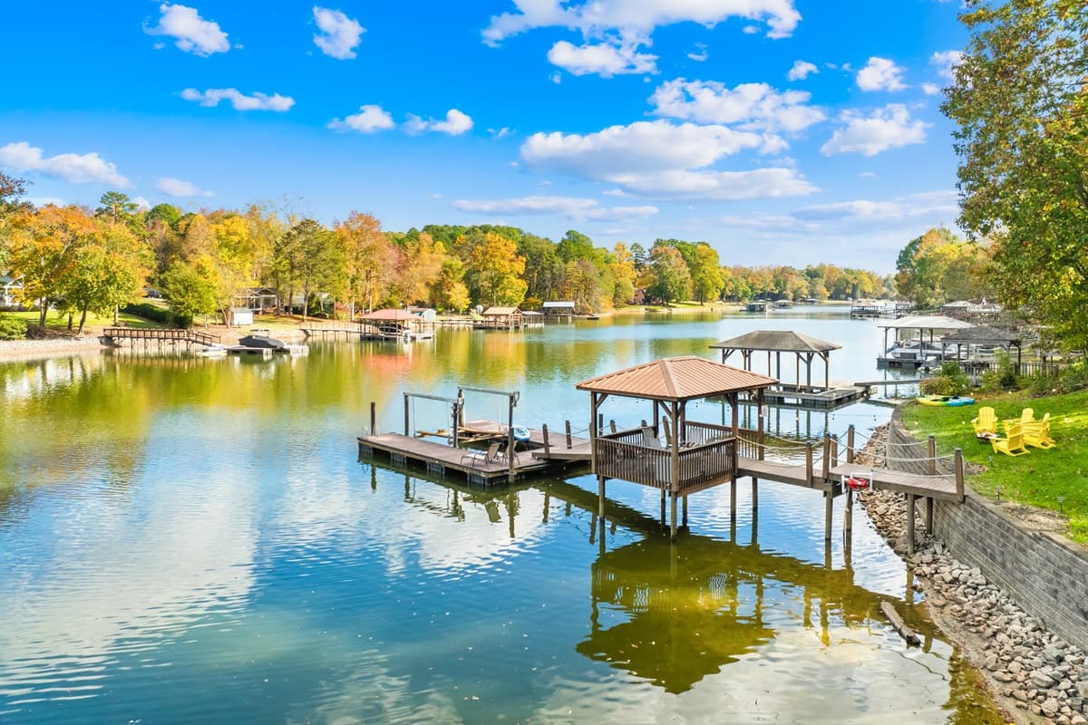 A covered dock and boathouse make lake days effortless, with fall color framing the water.