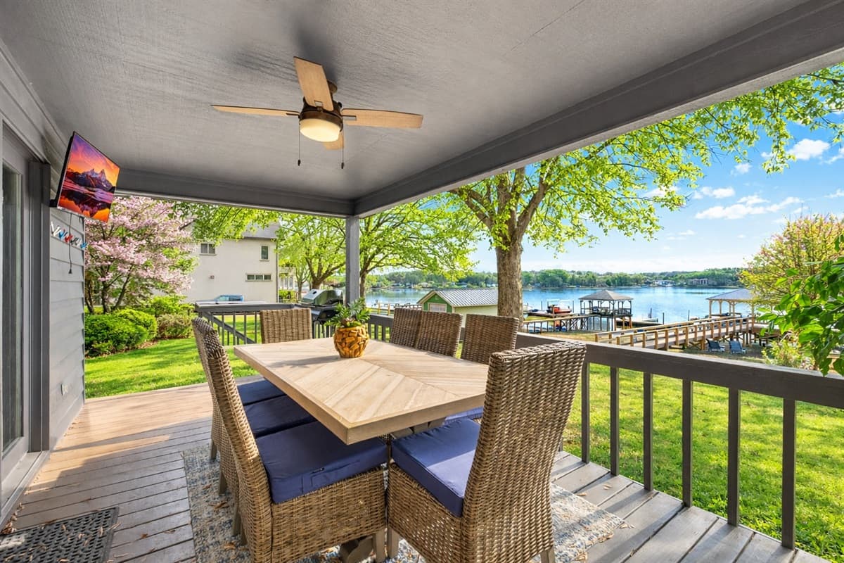 Enjoy meals at the covered porch dining table with views of the lake just beyond the railing.